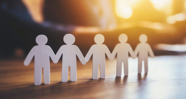 The EAP Is Not a Wellbeing Strategy and the Gap Is Costing You More Than You Think image Paper people holding hands, representing workplace wellbeing and support