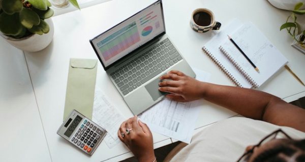 Blog image Person working at a desk with a laptop, calculator and paperwork
